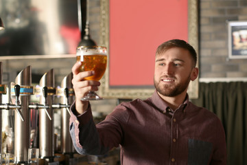 Bartender with glass of beer in bar