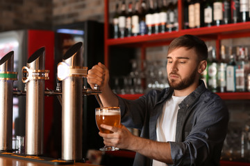 Bartender pouring beer into glass in bar