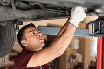 Male mechanic fixing car in service center