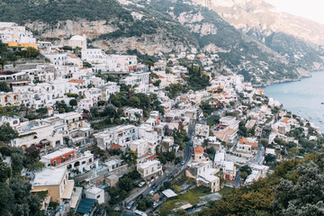 Fototapeta premium The coast of Positano, Amalfi in Italy. Panorama of the evening city and the streets with shops and cafes. Houses by the sea and the beach. Ancient architecture and temples
