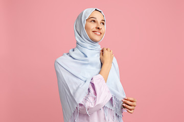 Happy arab woman in hijab. Portrait of smiling girl, posing at pink studio background. Young emotional woman. The human emotions, facial expression concept. Front view.