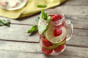 Mason jar with strawberry mojito on wooden table
