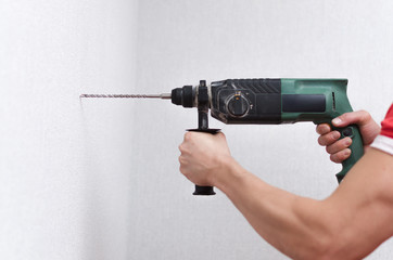 Builder worker drills a wall with a perforator. Home repair concept.