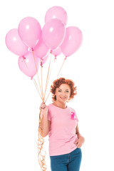 happy mature woman holding bunch of pink balloons and smiling at camera isolated on white, breast cancer concept