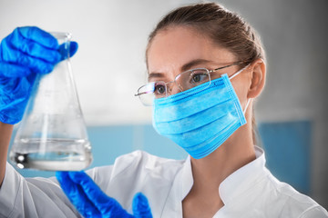 Scientist holding glass flask with sample in laboratory