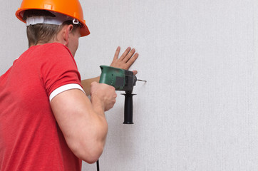 Builder worker drills a wall with a perforator. Home repair concept.