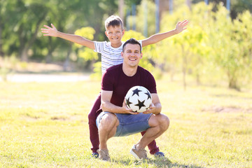 Little boy and his dad with soccer ball outdoors