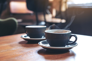 Closeup image of two blue cups of hot  coffee on vintage wooden table in cafe