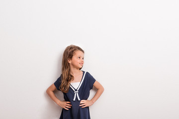 Portrait of a small girl in studio on a white background, hands on hips.