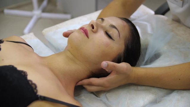 Woman doing neck massage at the reception of the chiropractor. Men's hands do massage of the cervical spine to an attractive girl.
