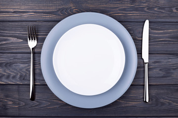 Serving wooden table with empty plate, fork and knife. Top view.