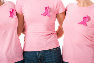 partial view of women with pink ribbons standing together isolated on white, breast cancer...