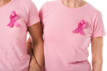 cropped shot of women with pink ribbons holding hands isolated on white, breast cancer awareness...