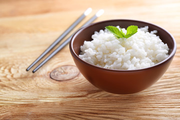 Bowl with boiled white rice on wooden table