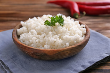 Bowl with boiled white rice on wooden table