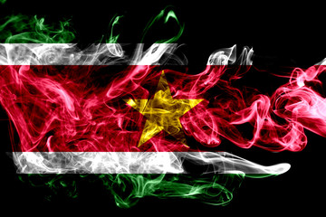 National flag of Suriname made from colored smoke isolated on black background. Abstract silky wave...