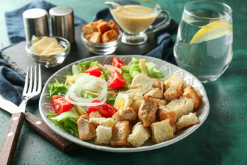 Plate with tasty Caesar salad on table