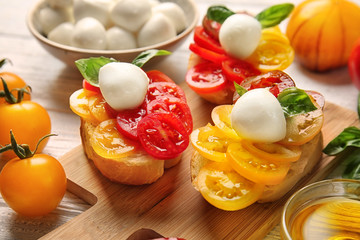 Tasty sandwiches with mozzarella cheese and fresh tomatoes on wooden board, closeup