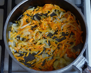 Roast in a frying pan and on a gas stove grated carrots and onions for cooking a delicious borsch.