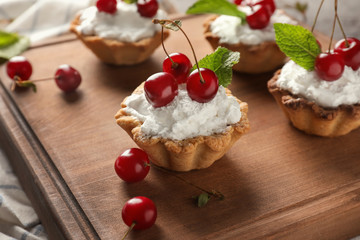 Delicious tartlets with cherries on wooden board