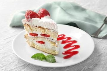 Plate with piece of delicious strawberry cake on table