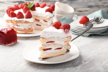 Plate with piece of delicious strawberry cake on table