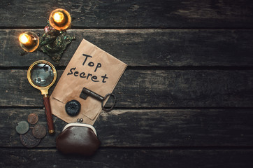Top secret documents file, key, magnifying glass and wallet with coins on the detective spy agent...