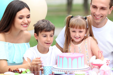 Happy family celebrating birthday at table outdoors