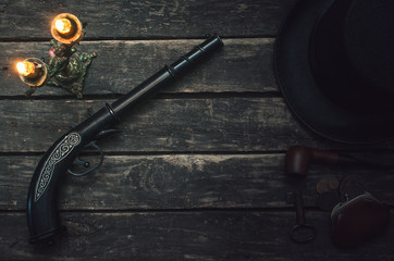 Musket gun, bowler hat, smoking pipe, wallet and ancient key on wooden table background.