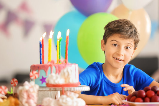 Cute little boy at table with birthday cake