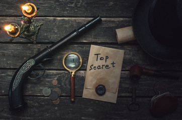 Top secret documents file, magnifying glass, smoking pipe, bowler hat and wallet with coins on the...