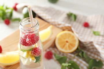 Glass bottle of fresh raspberry mojito on table