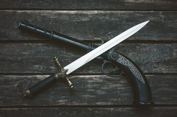 Musket gun and dagger knife on wooden table background.