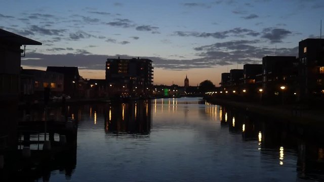 A view over the Delftse Schie in Delft at night, we see the Old Church, oude kerk, in the distance.