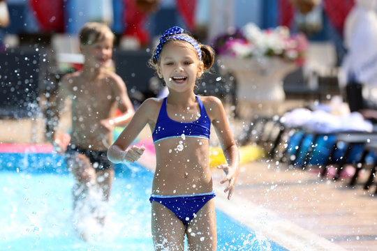 Cute children playing in swimming pool on summer day