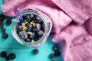 Glass jar with tasty blueberry smoothie on color wooden table, top view