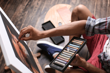 Young African-American artist drawing picture in workshop