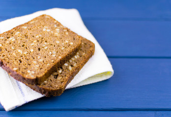 Black bread with seeds on a wooden blue background.