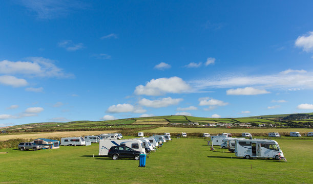 Motorhomes and campervans parked on a camping site in beautiful field in summer with blue sky