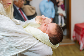 The mother holds the child on her hands during the rite of baptism.
