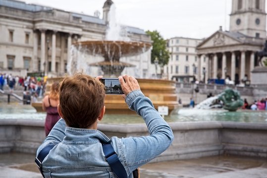 Tourist takes a photo with her smartphone in Trafalgar Square