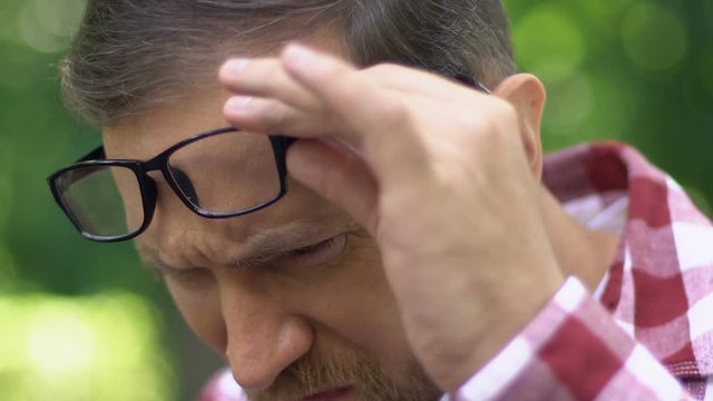 Cataract disease, man with poor eyesight looking at phone, bad lens fitting