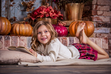 Happy little girl is reading book. Happy little girl and pumpkin. © alatielin