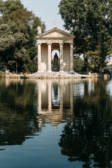 Fototapeta na wymiar Sculptures in the parks of Rome, nature and architecture. Ancient monuments of culture. Arches and columns, fountain and lake. Flowering plant