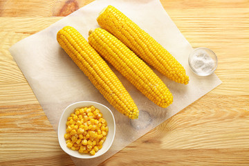 Tasty corn cobs, kernels and salt on wooden table