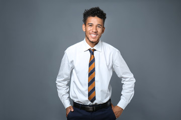 Handsome African-American businessman on grey background