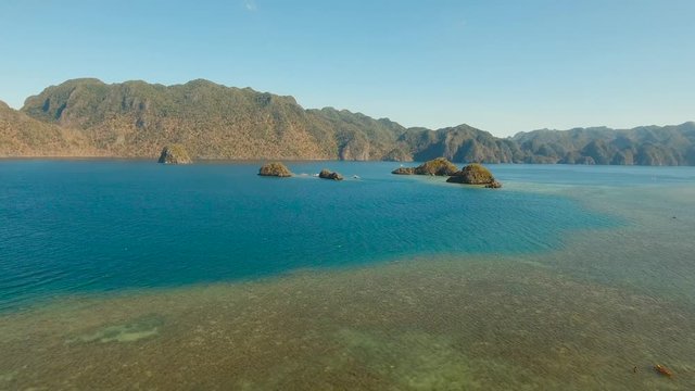 aerial footage islands in lagoon with turquoise water and coral reef. tropical seascape blue sea, azure lagoon. Busuanga, Palawan Flying over the azure surface ocean. Travel concept