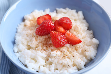 Bowl with delicious rice pudding and strawberry, closeup
