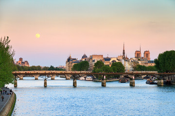 Fototapeta na wymiar Full moon rise at a pink twilight over the Seine in Paris, France 