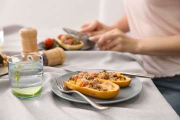 Plate with meat stuffed zucchini boats and glass of water on table